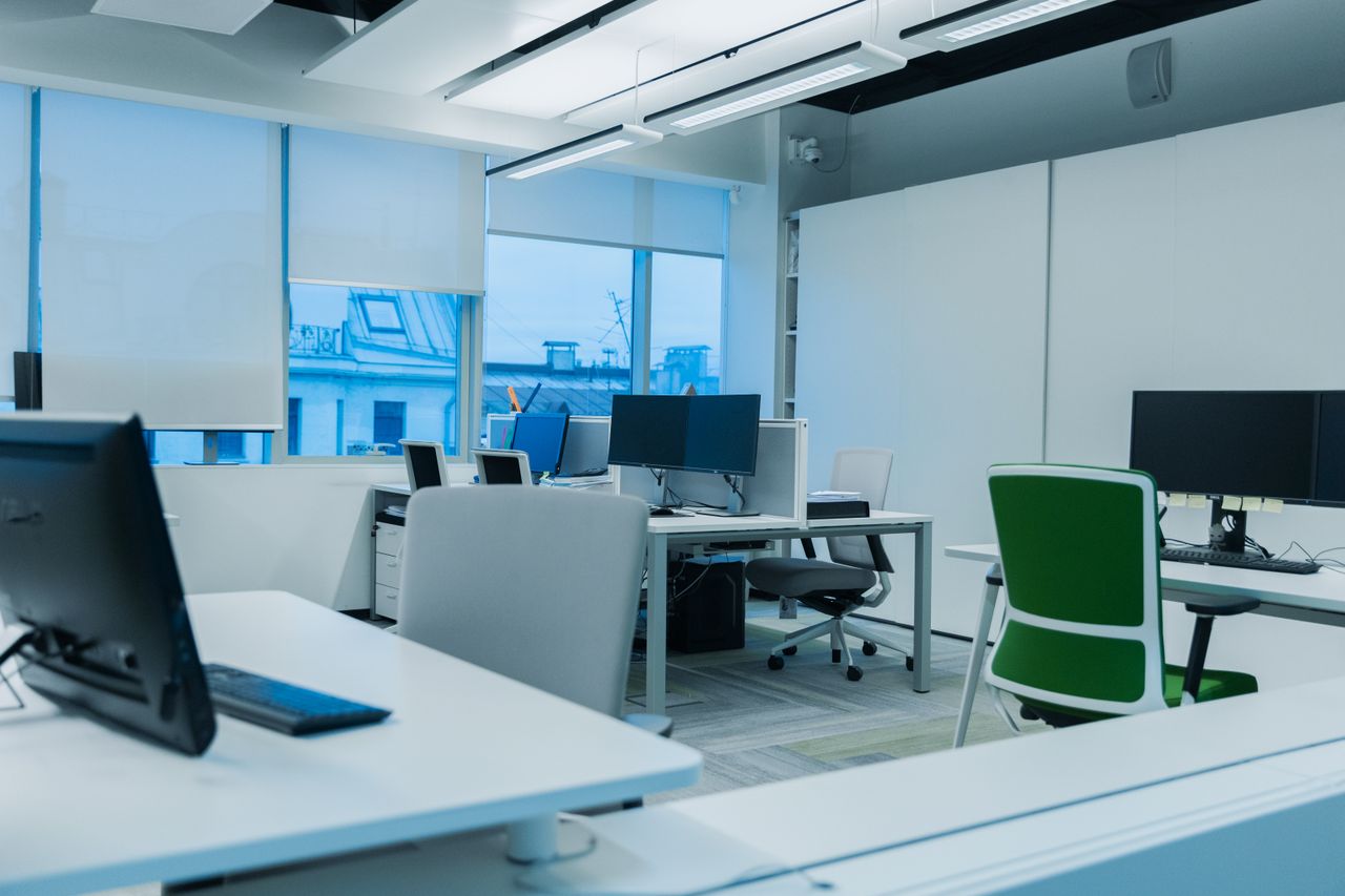 Ufficio luminoso con scrivanie bianche, monitor e sedie da ufficio
