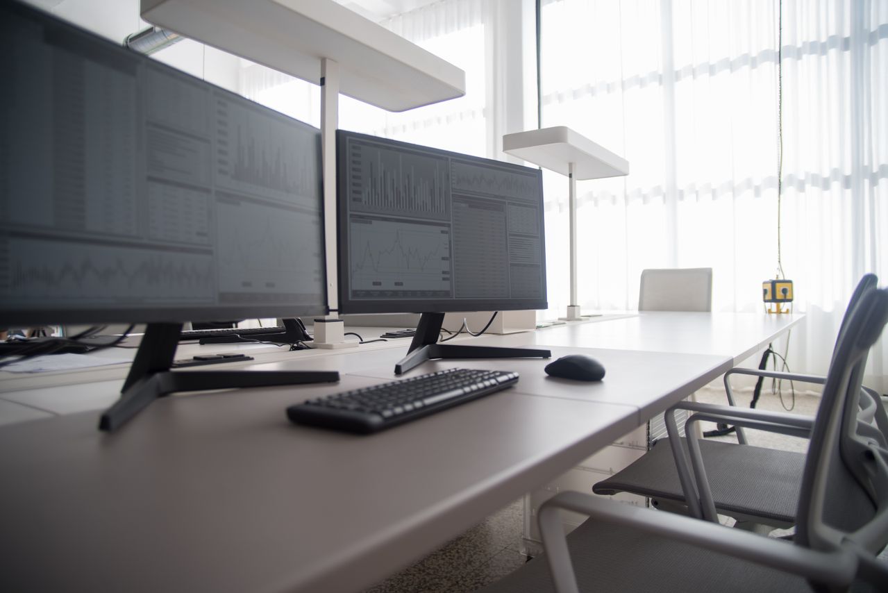 Postazione di lavoro con due monitor, tastiera, mouse e sedia con braccioli